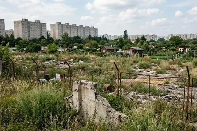 Zarastená plocha starej chemickej skládky na okraji mesta — lokalita so starou priemyselnou záťažou